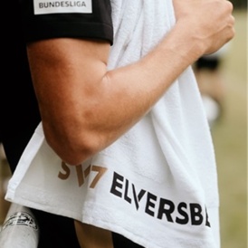 Eine Person hält ein weißes Badetuch mit beige-schwarzer „SV 07 Elversberg“-Aufschrift.